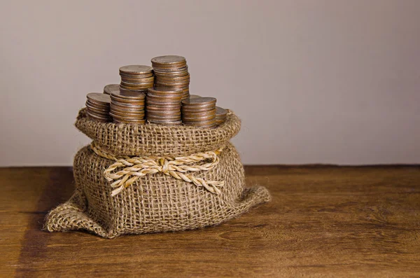 Bags filled with coins on wooden table — Stock Photo, Image