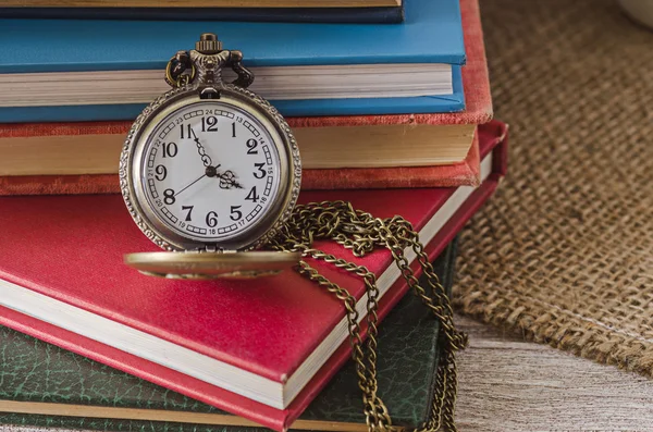 Кишеньковий або підвісний годинник на тлі старих книг — стокове фото
