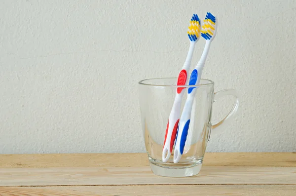 Escova de dentes par em vidro na mesa de madeira — Fotografia de Stock