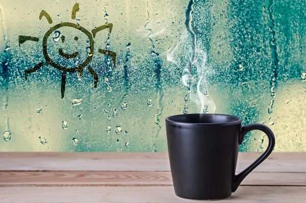 Xícara de café preto com fumaça e sinal de sol na água gotas de vidro wi — Fotografia de Stock