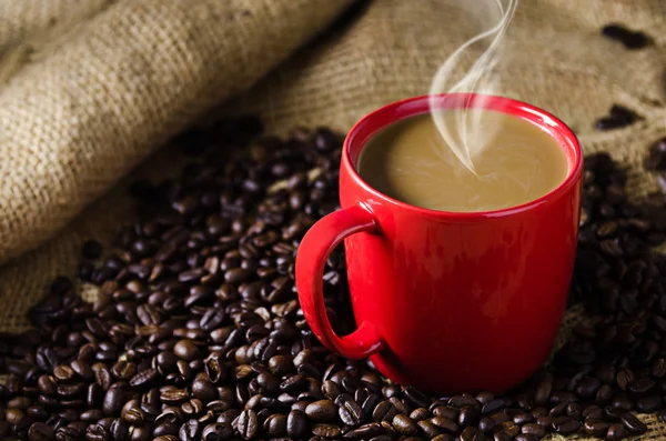 Tasse à café avec fumée et grains de café autour — Photo