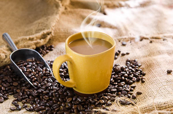 Tasse à café avec fumée et grains de café autour — Photo