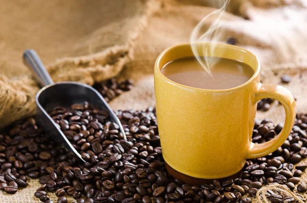 Taza de café con humo y granos de café alrededor — Foto de Stock