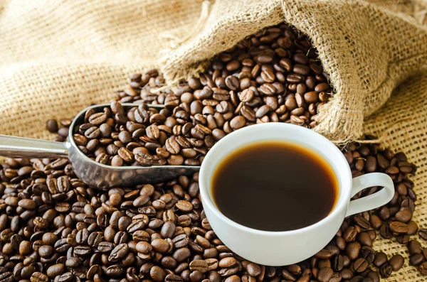 White coffee cup with smoke and coffee beans around — Stock Photo, Image