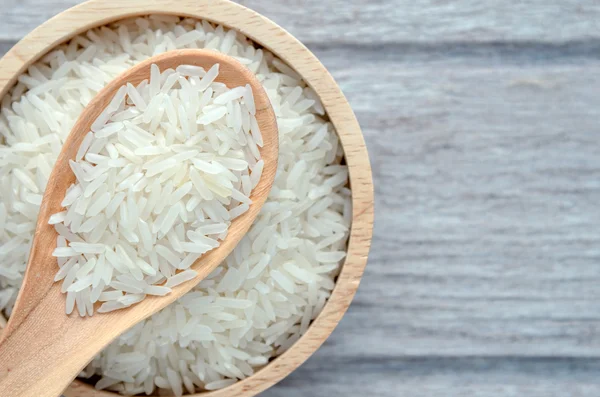 Arroz sin cocer en un tazón sobre fondo de madera blanca — Foto de Stock