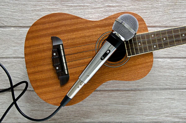 Mikrofon a ukulele kytara na bílý dřevěný stůl — Stock fotografie