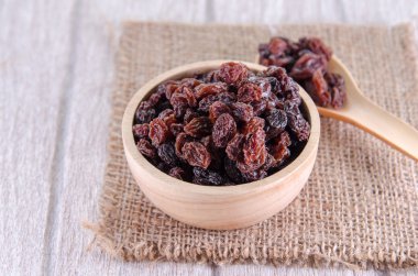 ahşap kase ve Beyaz ahşap masa kaşık kuru üzüm