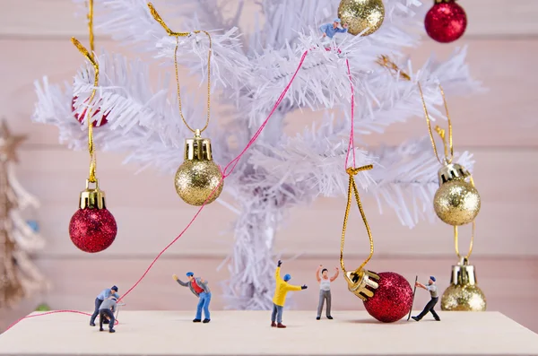 Miniature people try to ornament Christmas tree — Stock Photo, Image