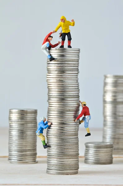 Escaladores en miniatura equipo de escalada en pila de monedas — Foto de Stock