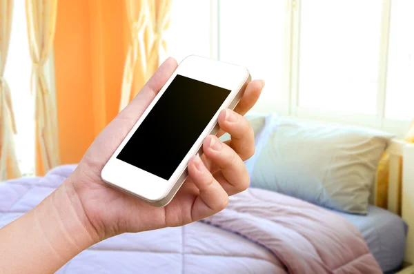Mão mulheres segurando o tablet do telefone no fundo desfocado quarto — Fotografia de Stock