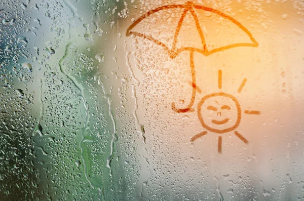 Draw sun holding umbella on natural water drops glass window bac — Stock Photo, Image