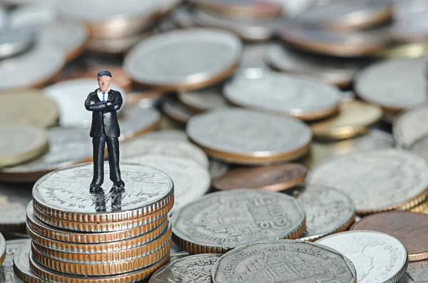 Hombre de negocios en miniatura de pie en la pila de monedas —  Fotos de Stock