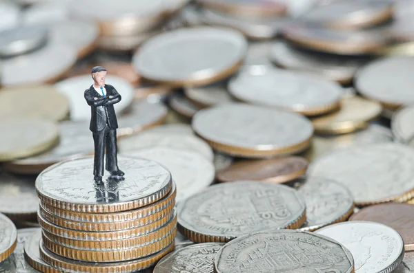 Miniatyr business man på stacken av mynt — Stockfoto