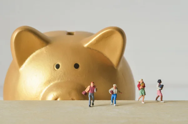 Miniature people run away from gold piggy bank — Stock Photo, Image