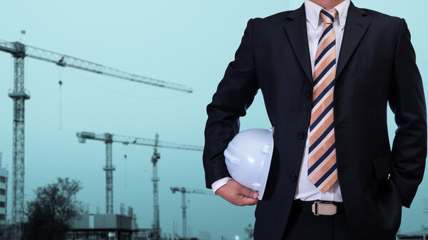 business man holding white safety helmet with construction site 