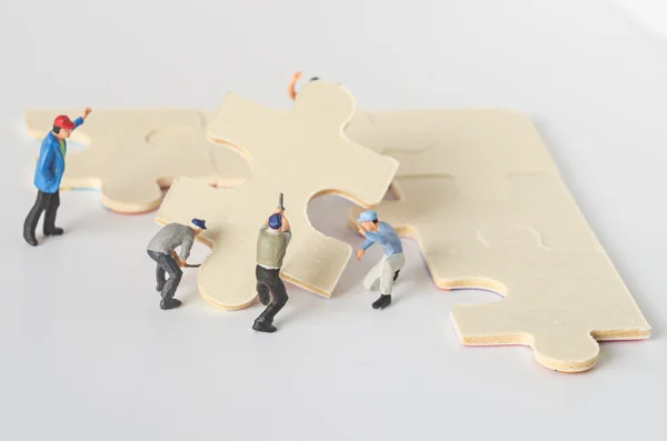 Miniaturowe pracownik zespołu spróbuj ukończyć puzzle układanki — Zdjęcie stockowe