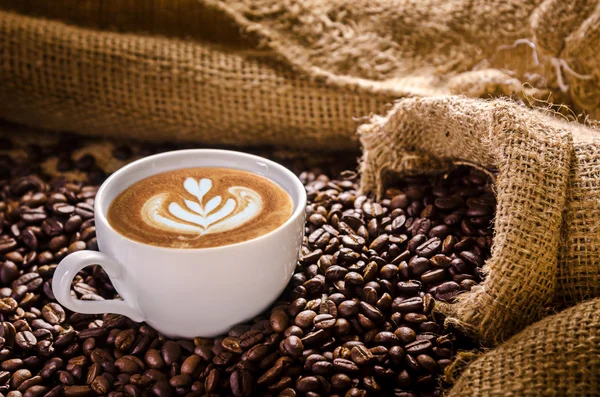 Witte koffiekopje en geroosterde koffiebonen rond — Stockfoto