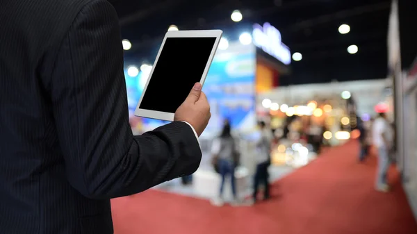 Empresário usando tablet com fundo de evento desfocado — Fotografia de Stock