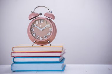 kahverengi çalar saat ve ahşap masa kitap yığını