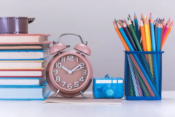 Potlood kleurvak, wekker en stapel boek over houten tafel — Stockfoto