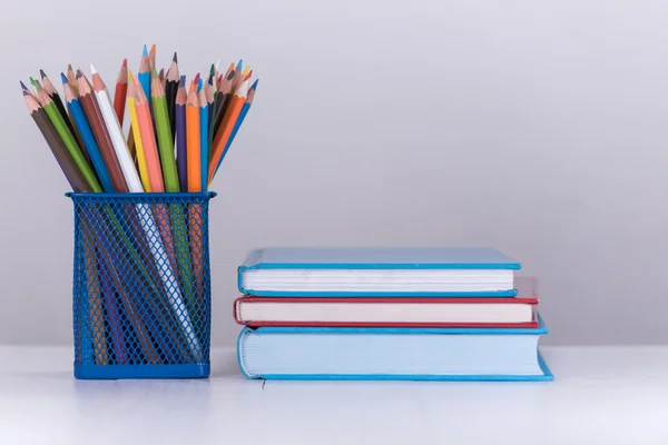 Farbstiftkasten und Bücherstapel auf Holztisch — Stockfoto