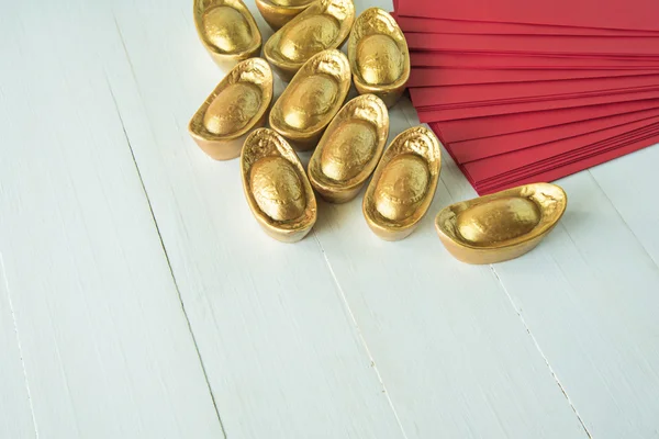 Chinese golden ingots and red envelope on wooden table : Chinese — Stock Photo, Image