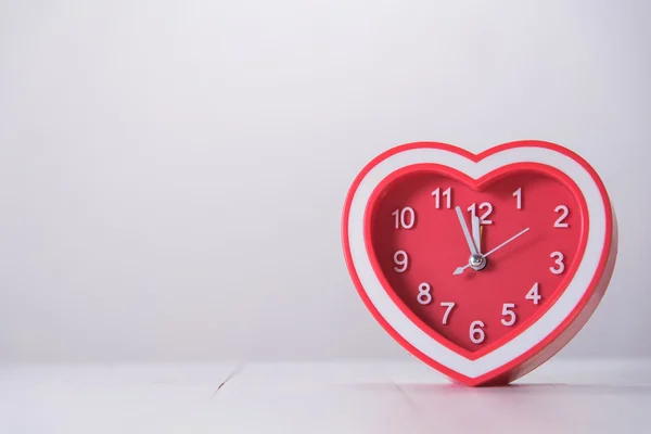 Reloj corazón rojo sobre mesa de madera blanca — Foto de Stock