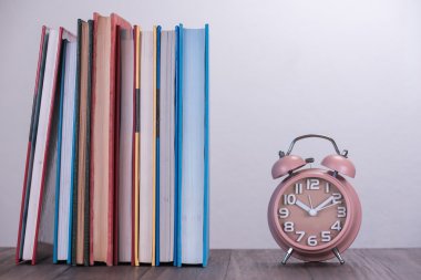 kahverengi çalar saat ve ahşap masa kitap yığını