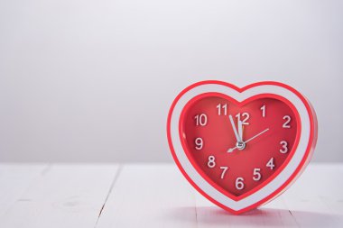 Kırmızı kalp saat beyaz tahta masada