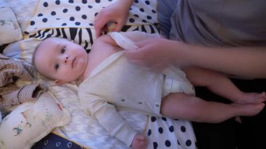 Yumuşak tutulan bebek, şefkatli eller ve battaniyeyle huzur içinde dinleniyor. Bakımlı Yetişkinler Yeni Doğan 'ı Nazikçe Sarmalayarak Rahatlatıcı Dokunuş ve Konforlu Battaniyeyle Değişen Mat' ta