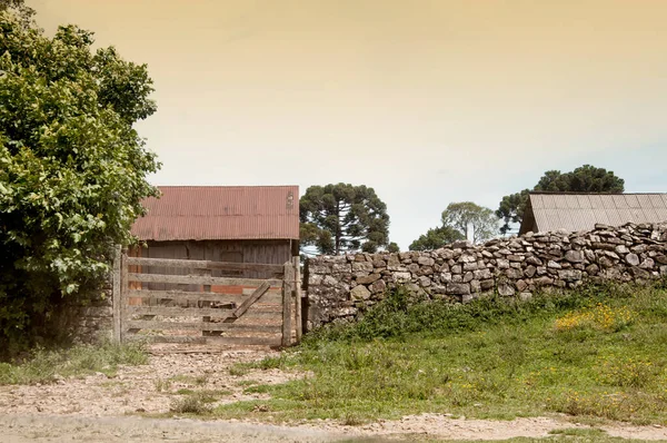  Arka planda taş duvarlı ve barakalı eski çiftlik kapısı.