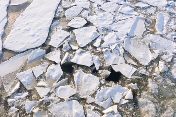 white and gray ice texture on a winter river, broken ice floe covered with snow with a textured surface, cracked and fragmented ice floating on frozen water on a cold day, icy pattern, background