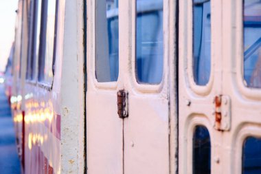 Tramvay desenleri, pencereli ön kapı ve eski demir bir tramvayın detayları arka plandaki diğer araçlarla birlikte şehir yolundaki trafik sıkışıklığında, yakın plan.