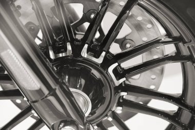 close up of American heavy vintage motorcycle of a famous brand on showcase, rim of the wheel with brake, part close-up, motorbike with shiny chrome detail in monochrome, black and white backgrounds