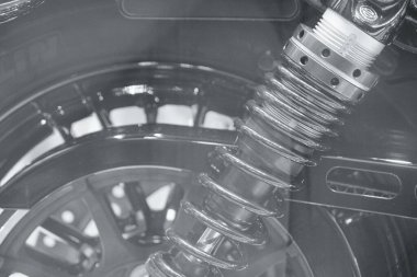 side of American heavy vintage motorcycle, parts of transmission and absorber spring with elements on showcase, close-up, motorbike with shiny chrome detail in monochrome, black and white backgrounds