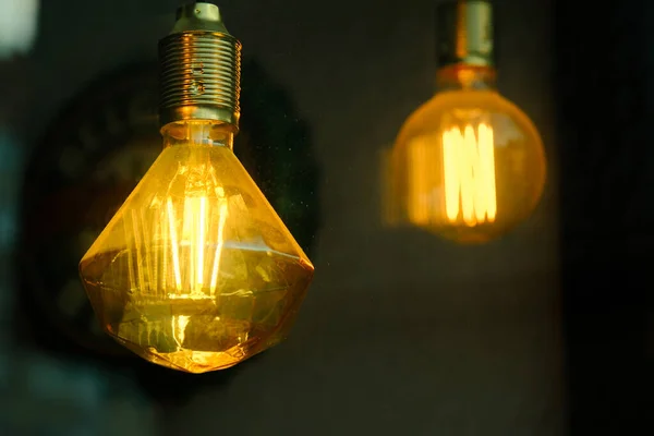 glowing yellow tesla decorative glass light bulb in the dark, stylish electrical Edison hanging lamp for interior art spotlight illumination and decoration, retro design home decor detail, idea symbol