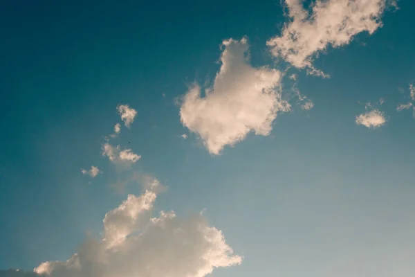 deep blue sky and high clouds in the sun rays at sunset, fluffy light heaven, bright skies with soft cumulus, abstract white cloud outdoors, weather background, beautiful cloudscape texture