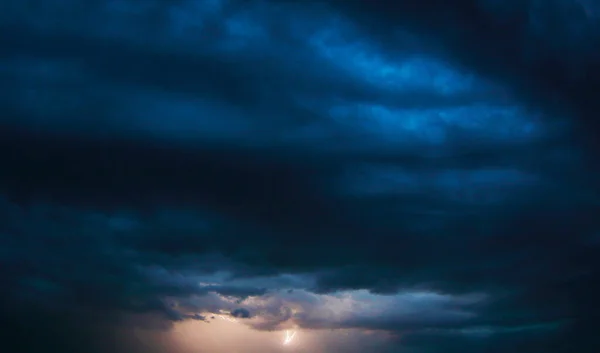 Stormy sky during a thunderstorm. Thunderous flash on the horizon of a dark blue sky. For background wallpapers and postcards.