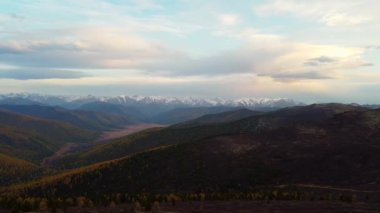 Dağ tepelerinin üzerinden uçmak. Gün batımında dağların ve bulutların panoramik manzarası