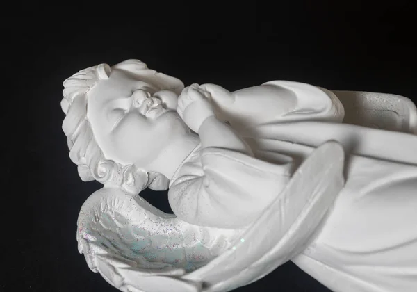 黑色背景的沉睡中的白色天使雕塑 — 图库照片