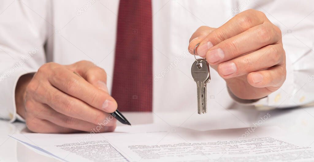 Businessman signing contract with keys in hand. real estate agreement concept. banner