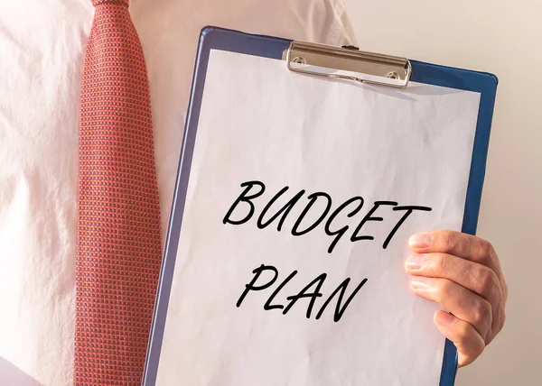 Budget plan text on paper board in businessman hands, money concept
