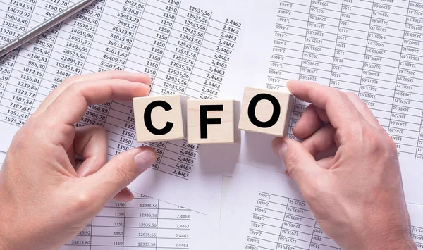 CFO acronym, chief financial officer concept. cube in male hands on office table, top view