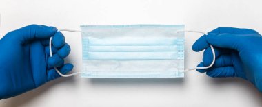 Eldivenli doktorun elleri tıbbi koruyucu maske takıyor. Maske, üst görüş, fotokopi alanı olan pankart..