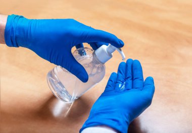 Eldiven takan ya da salgın sırasında el dezenfeksiyonu için dezenfektanı kullanan erkek eller. Ellerini sterilize et..