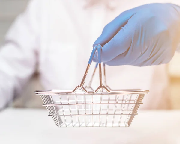 Compras de metal cesta vazia na mão masculina em luva protetiva azul. compras durante o conceito de bloqueio coronavírus — Fotografia de Stock