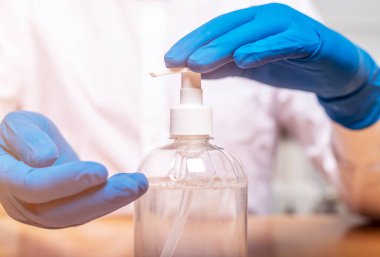 Eldiven takan ya da salgın sırasında el dezenfeksiyonu için dezenfektanı kullanan erkek eller. Ellerini sterilize et..