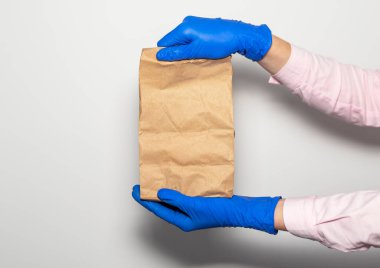 Güvenli teslimat konsepti. Beyaz arka planda koruyucu eldivenlerle kuryenin elinde bir paket ya da el işi. Güvenli internet alışverişi.