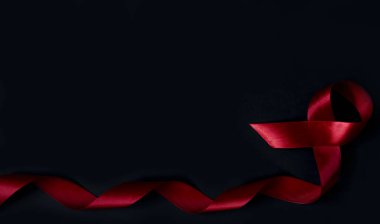 Dünya AIDS Günü konsepti. Kırmızı kurdele siyah arkaplanda izole edilmiş. Kopyalama alanı olan pankart.
