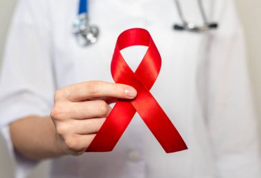 AIDS ve HIV dünya desteği için kırmızı kurdele, yakın çekim. Kadın doktorun eli..